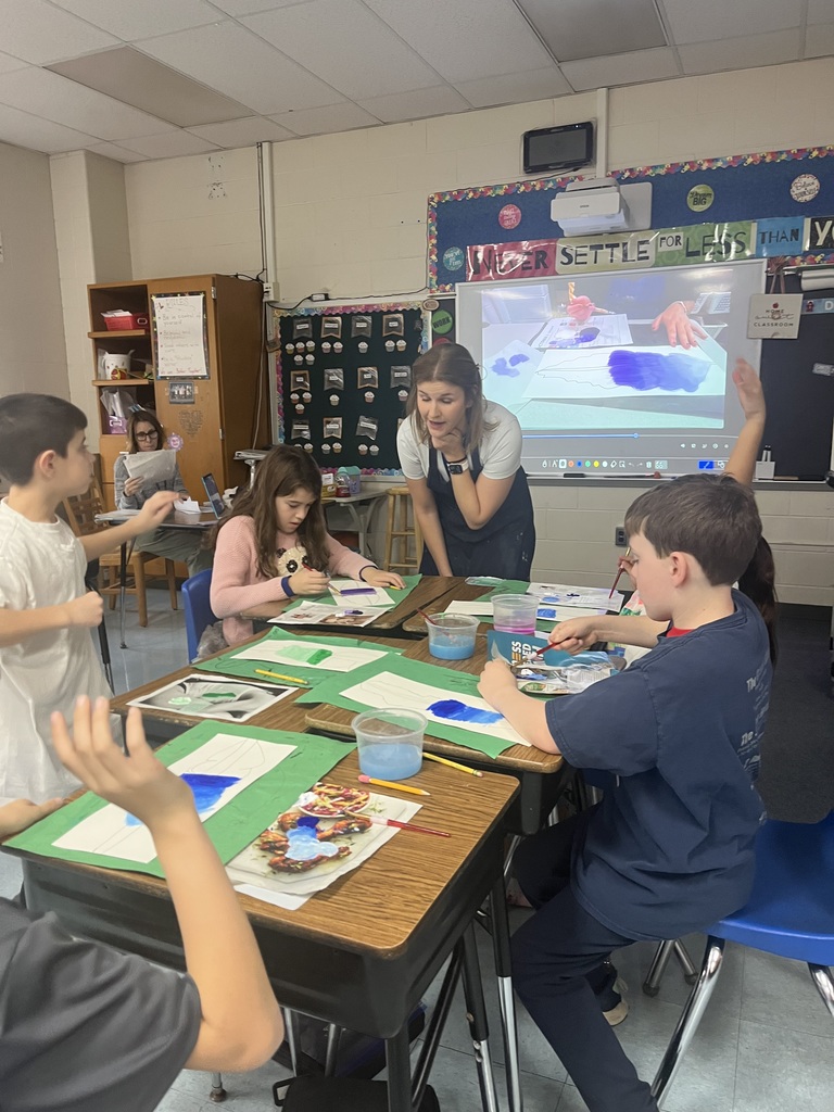 Students painting their feather and teacher giving suggestions.