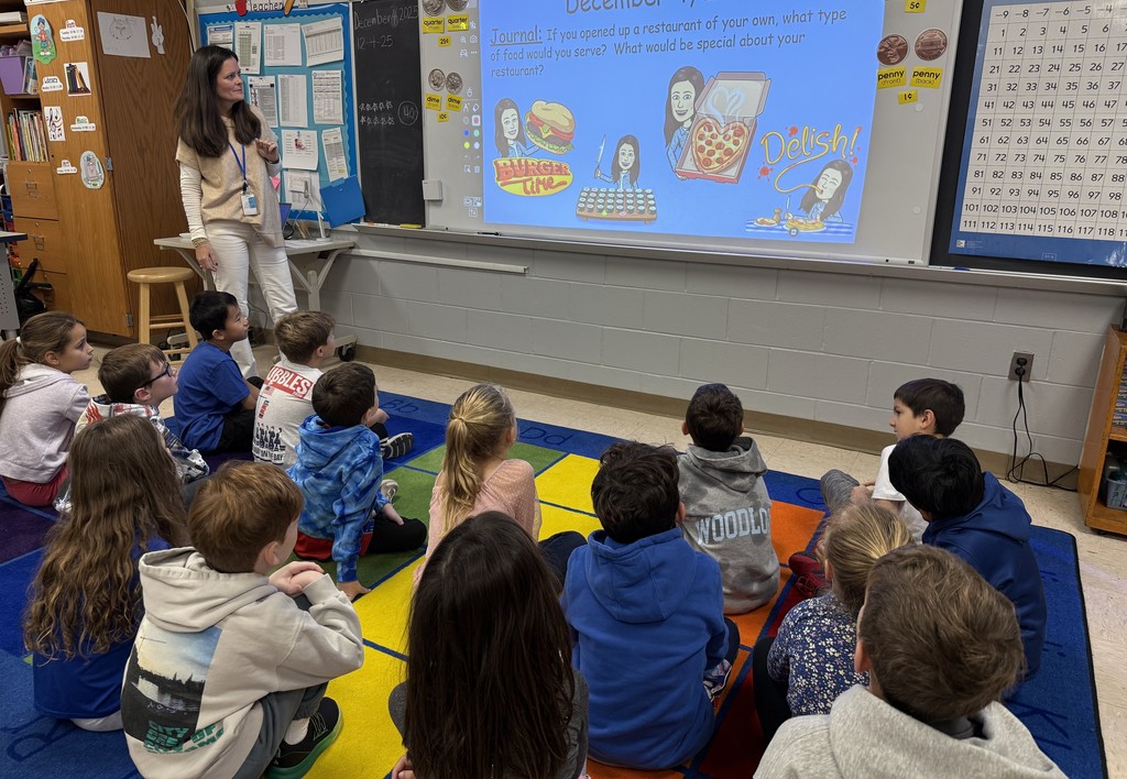 second grade class sitting on the rug, sharing the restaurants they would open