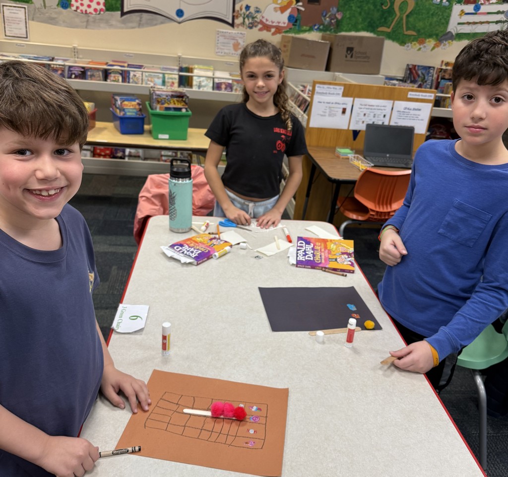 three students standing at a table  at Book Club