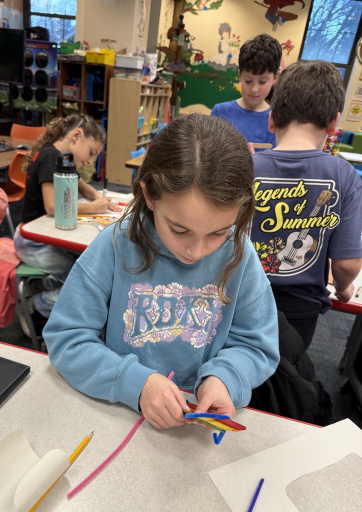 a  student sitting at a table, working on a craft at Book Club