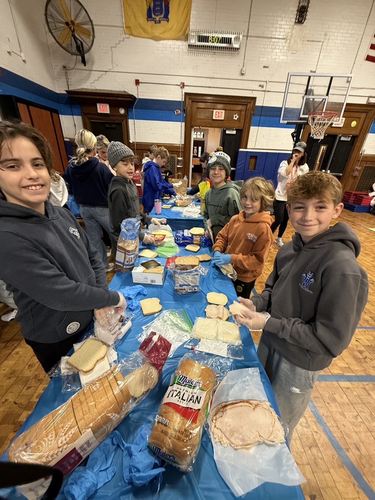 5th grade students standing together while making sandwiches