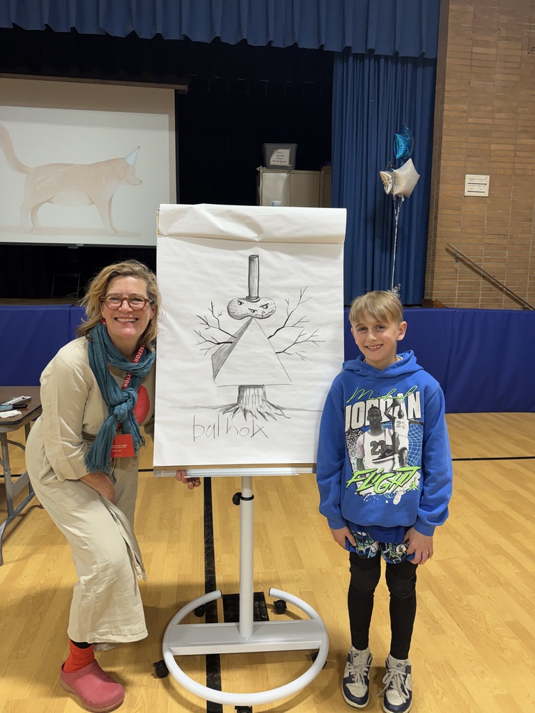 Author is photographed with a student next to the cartoon alien picture.