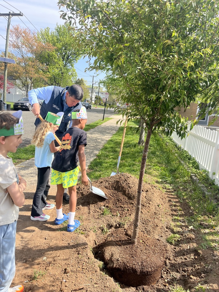 Mayor helps students shovel some dirt onto the new tree.