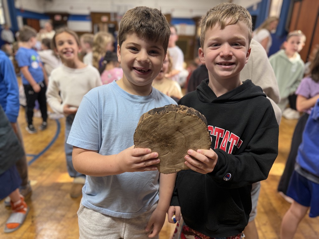 2 students holding a cross-section of a tree