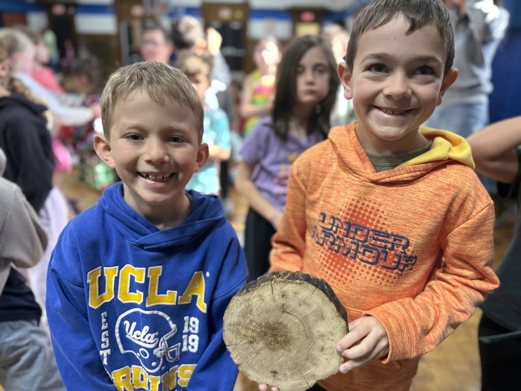 2 students holding a cross-section of a tree