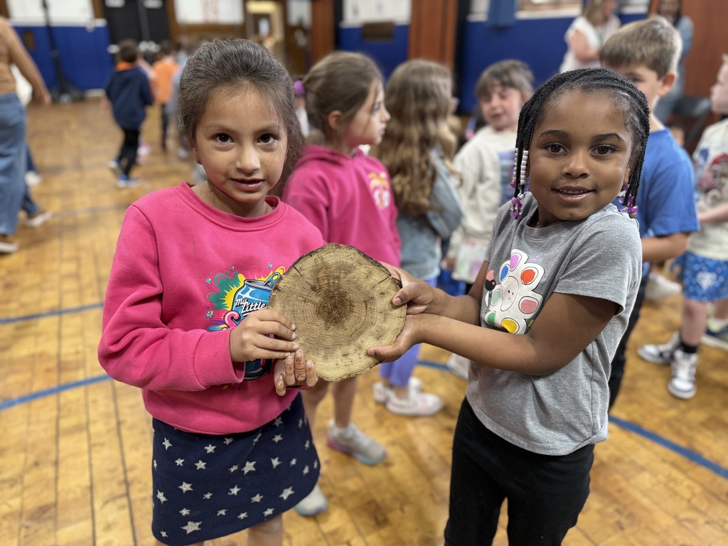 2 students holding a cross-section of a tree
