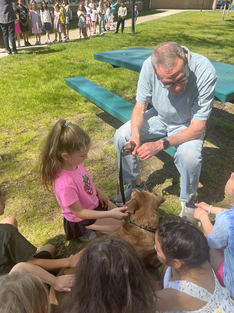Dog owner answers student questions as they pet the therapy dog.