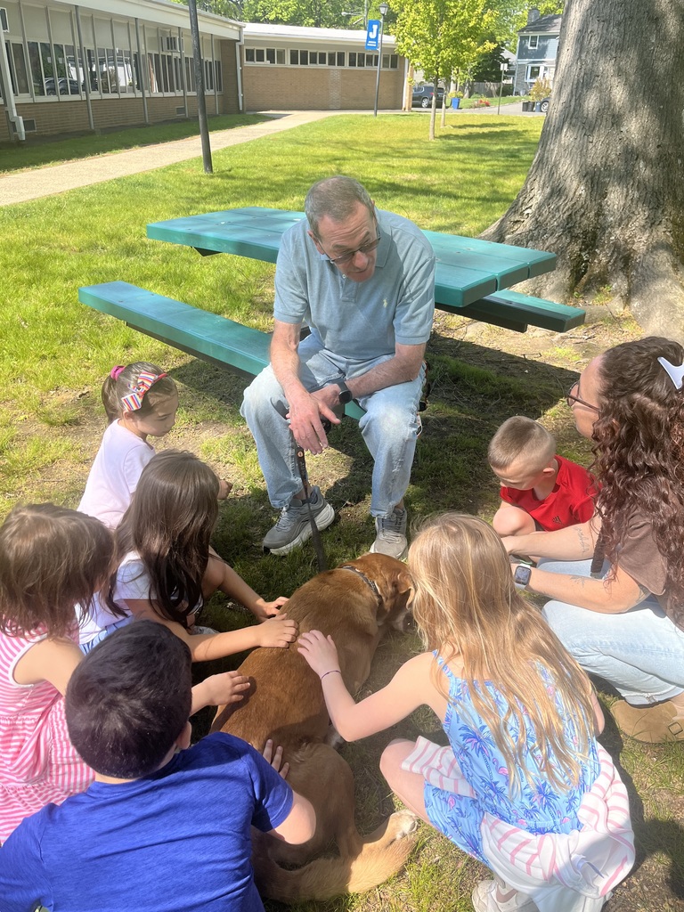 Dog owner answers student questions as they pet the therapy dog.