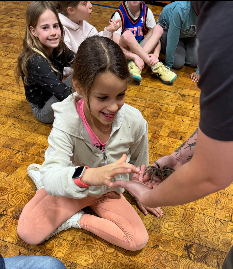students looking at presenter holding a bug