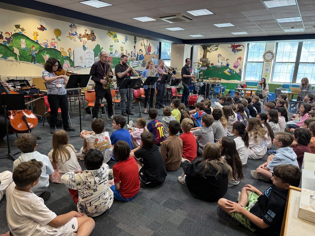 3rd grade students sitting, listening to an instrument demonstration