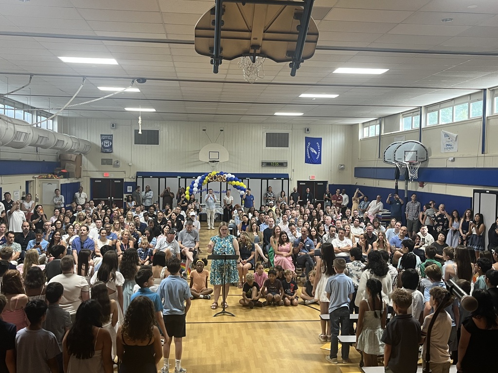 Music teacher leads the students in singing one last song at the Moving Up Ceremony for their families in the audience. 