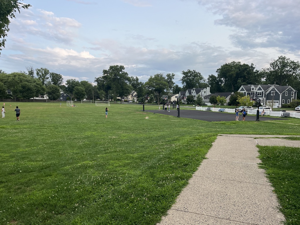 Students playing on the field and new blacktop on a beautiful evening.