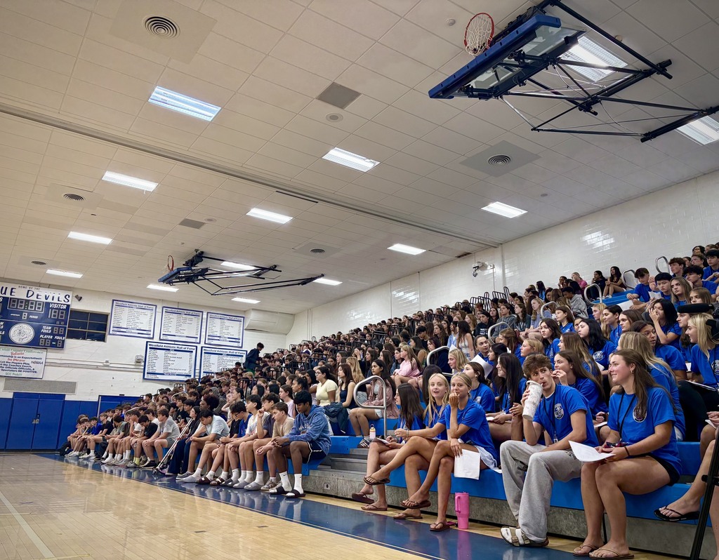 Gymnasium bleachers filled with new students and tour volunteers