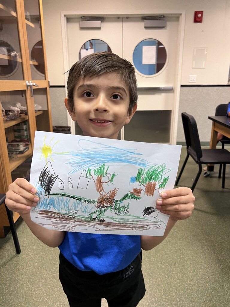 Student showing his dinosaur drawing