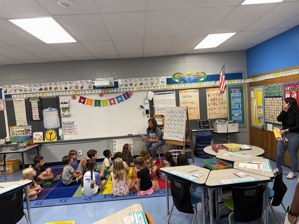 first grade teacher, sitting reading to class on the rug