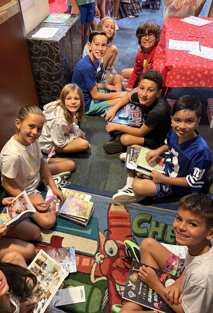 students sitting with their books from the book fair