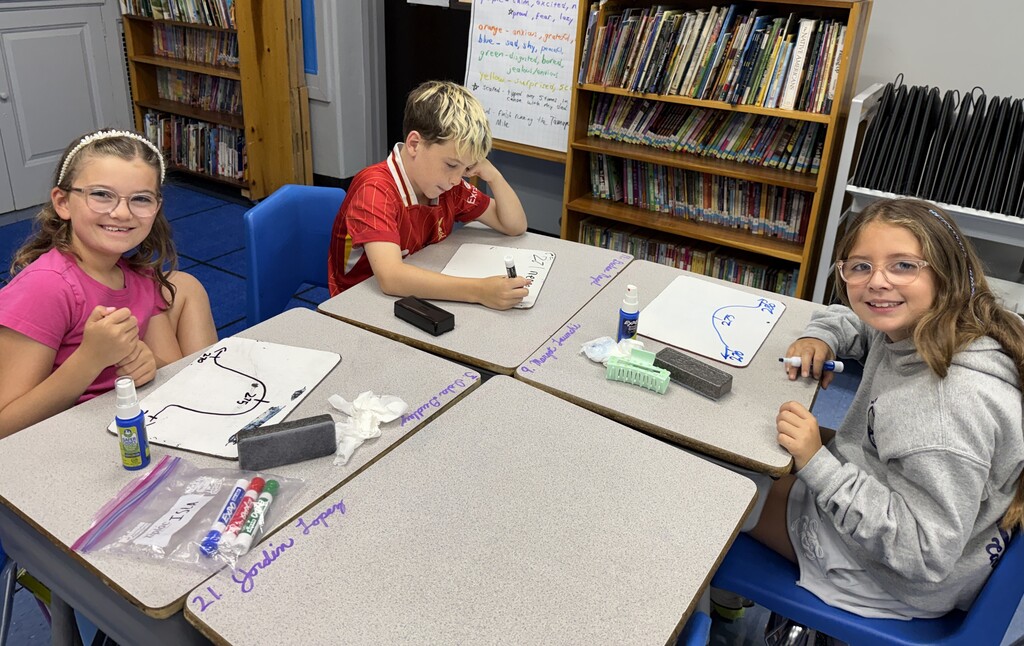 students sitting at their desks with white boards to practice rounding
