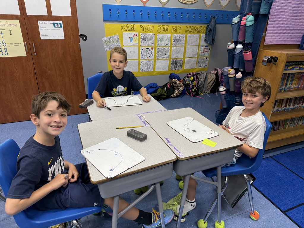 students sitting at their desks with white boards to practice rounding
