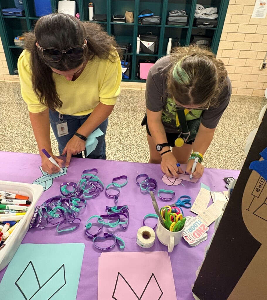 Two students at EIS signing Blue & Purple Ribbons for Suicide Prevention Month