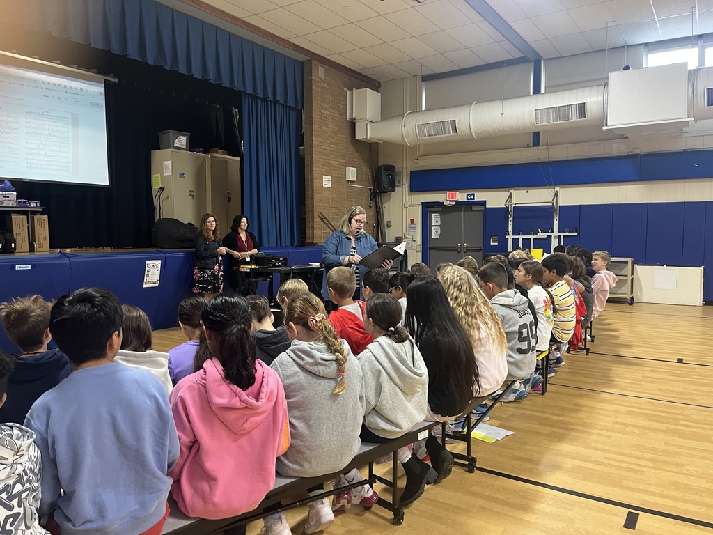 Students sitting on the benches facing the music teacher during chorus lesson