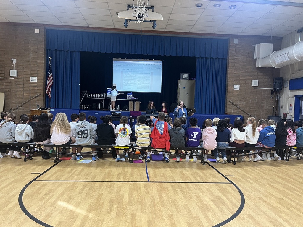 students sitting on the benches facing the music teacher during chorus lesson