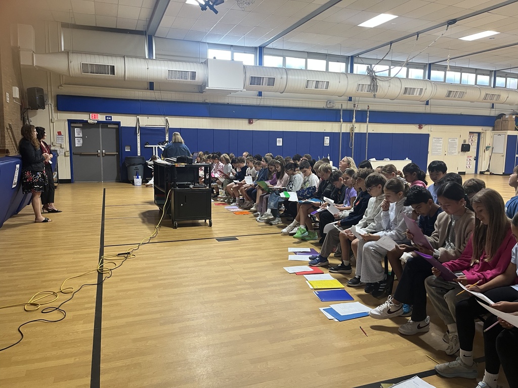 students sitting on the benches facing the music teacher and learning the new song