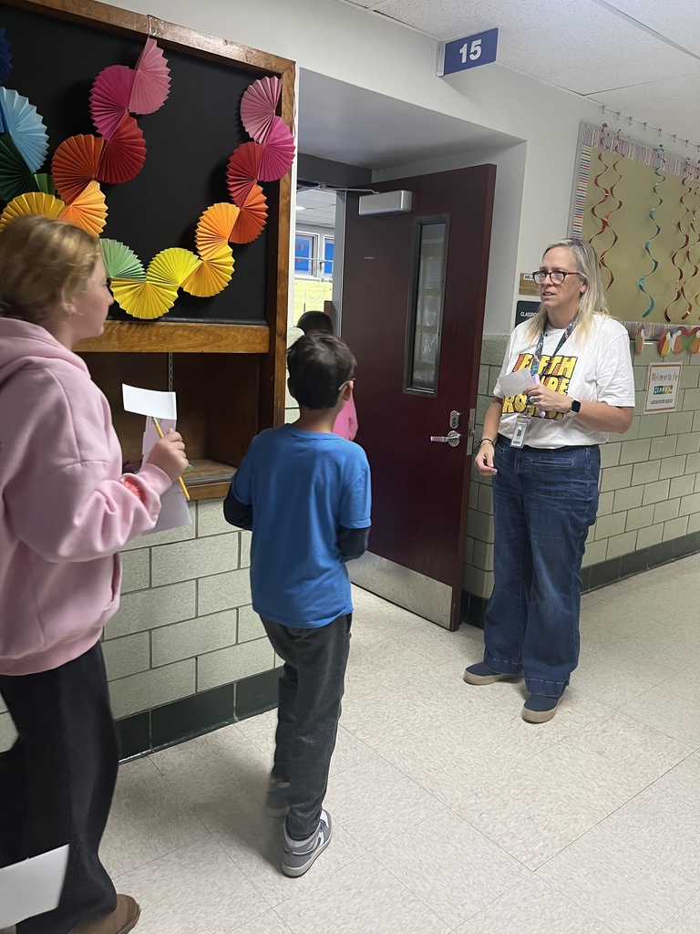 Teacher greets students at the door.
