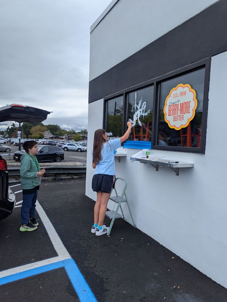 student painting a storefront