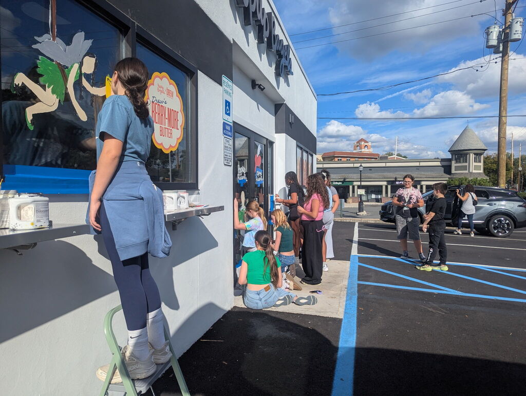 students painting a storefront