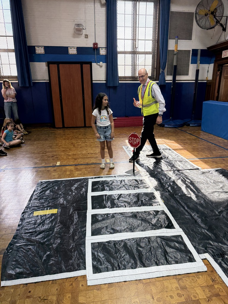 second grade girl practicing safely crossing at an intersection with the presenter