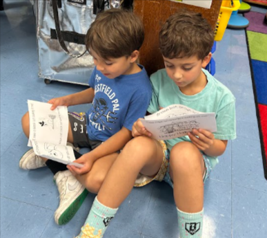 two first grade students, sitting on the floor reading