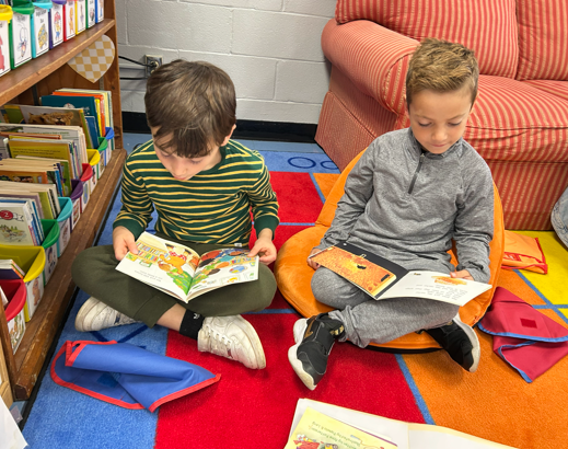 two first grade students, sitting on the rug reading