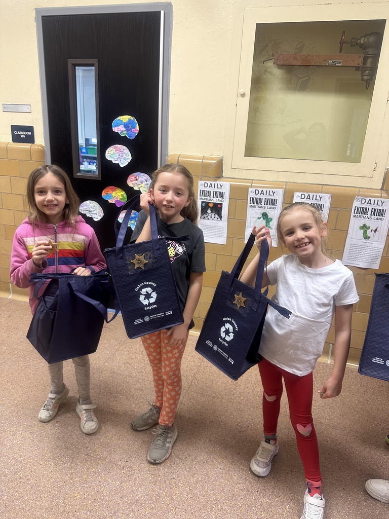 three second grade girls holding their recycling bags