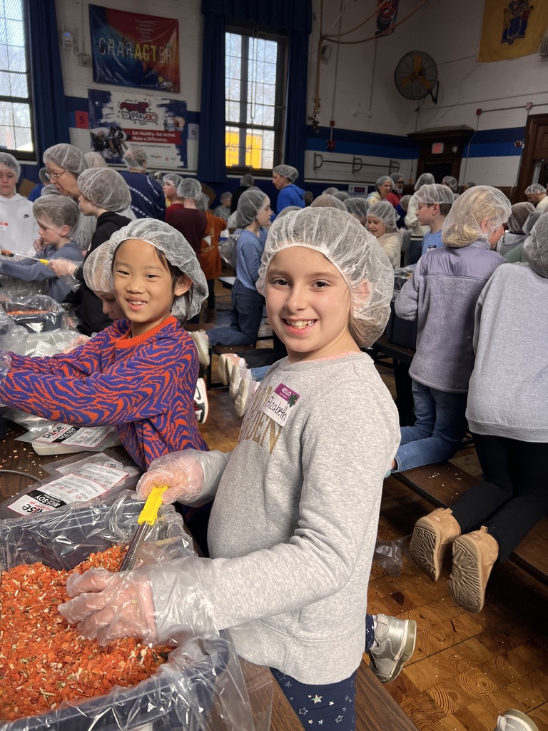 students working together to pack meals for community service week