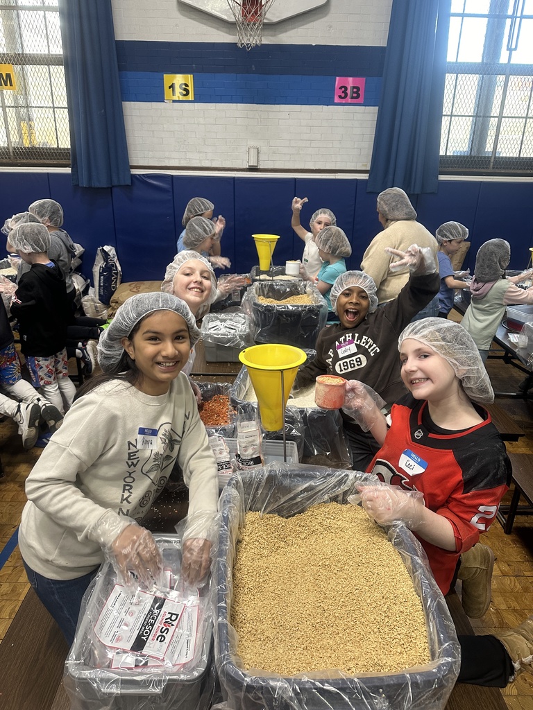 students working together to pack meals for community service week