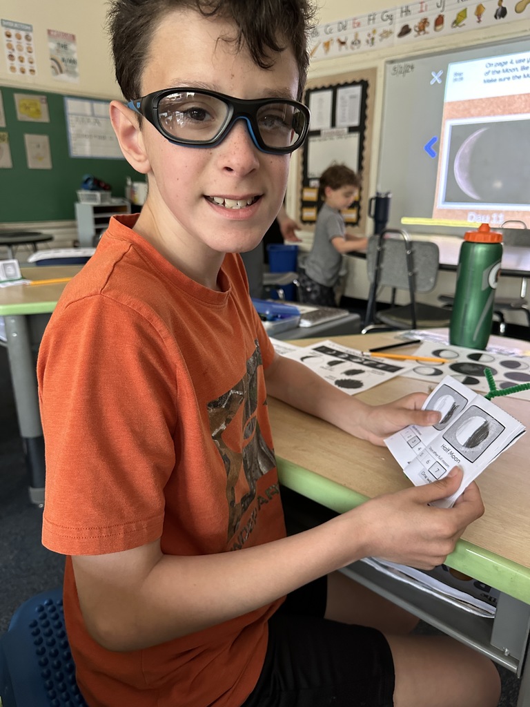 student holding the moon phase book they made