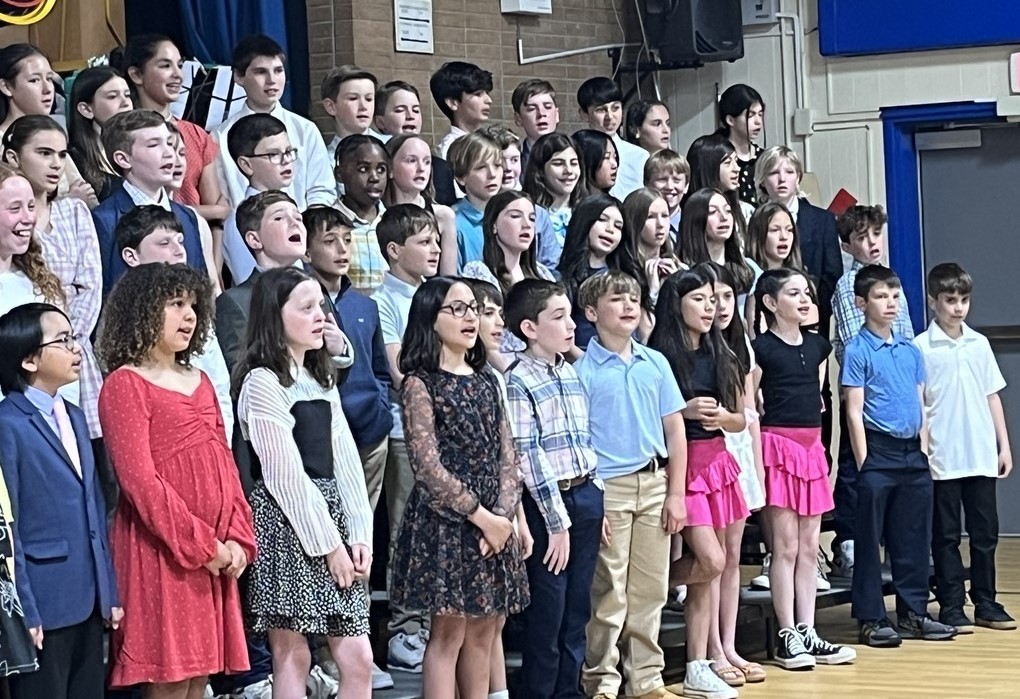 Group of students on stage, singing.