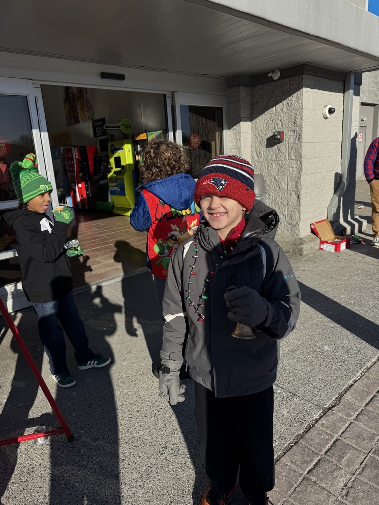 One student smiling while holding the Salvation Army bell. 