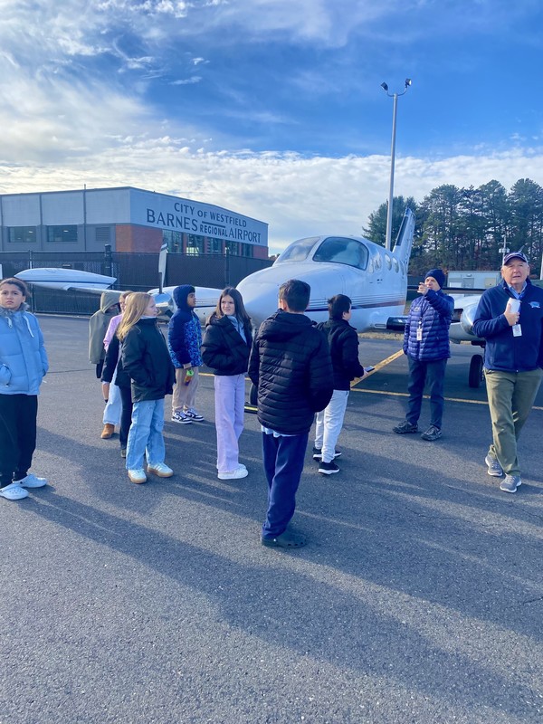 Students on runway with plane
