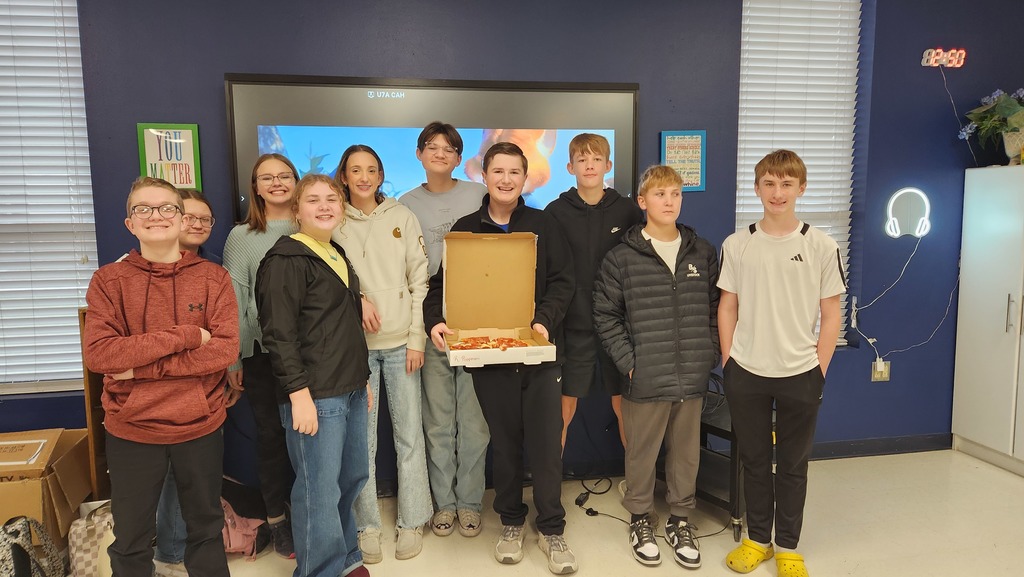 group of students holding a pizza