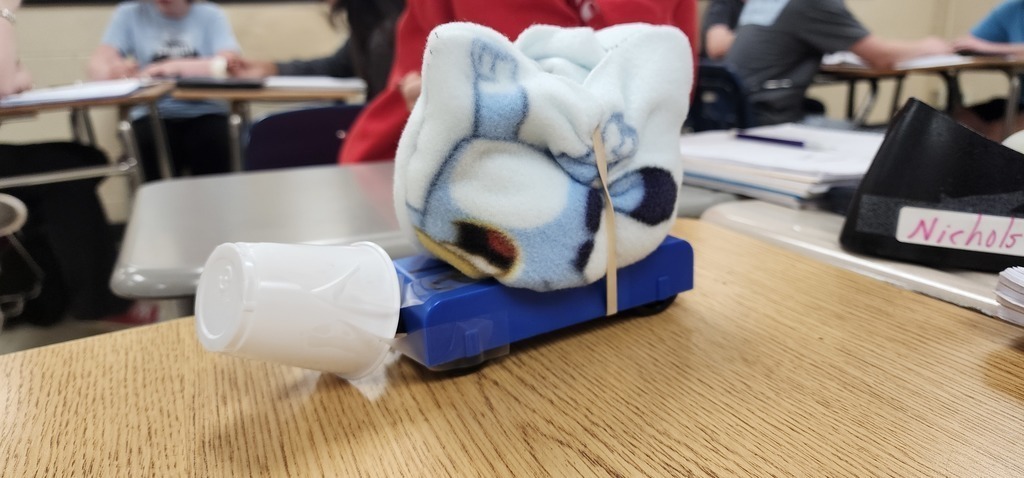This is the Physics  Egg Lab.  Each group was tasked with the objective of protecting an egg.  So, in the middle of all that 'stuff' is an egg.  After the car traveled down a ramp that was 27 books high (about 0.92 meters) three times, I unwrapped the egg and checked for fractures.  They had a limited budget and were allowed to purchase different materials.  They were allowed to bring one item from home that fit into a 6 inch x 6 inch area.  They had 3 minutes to build their car with bumpers and protection for the egg.  They were so innovative with their materials they brought from home.  After all of this, they had to calculate speed, kinetic energy and potential energy.  This is their final lab in a series of labs where they learned how to do calculations, write labs, understand the cart and how it moved, and measurement. Warrior Work Ethic in full force!