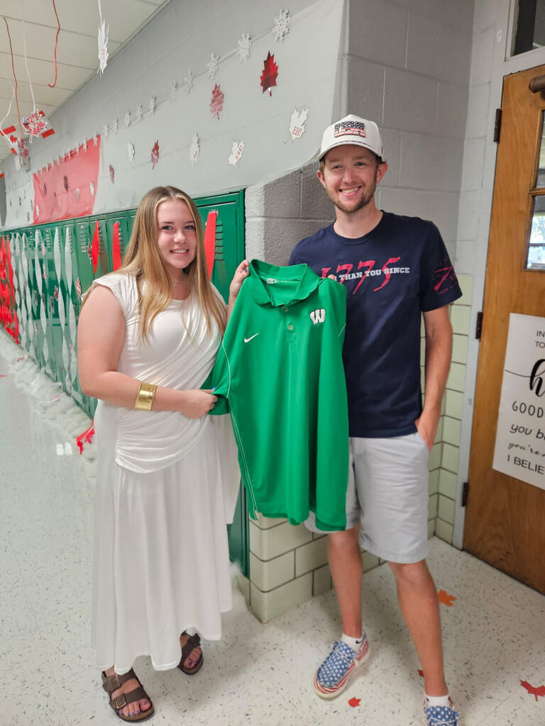 Maddie Verscha giving new staff member Ryan Hansen a golf polo.