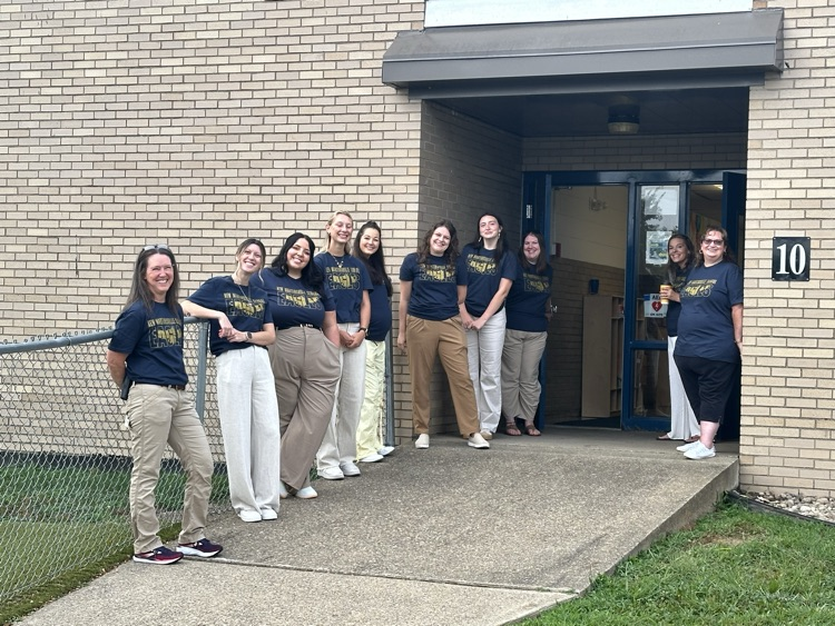 Welcoming our kiddos back!! Teachers on ramp wearingblue school shirts and makes
