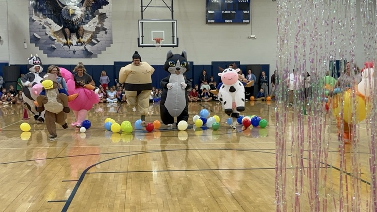 adults in blowups racing down the gym floor