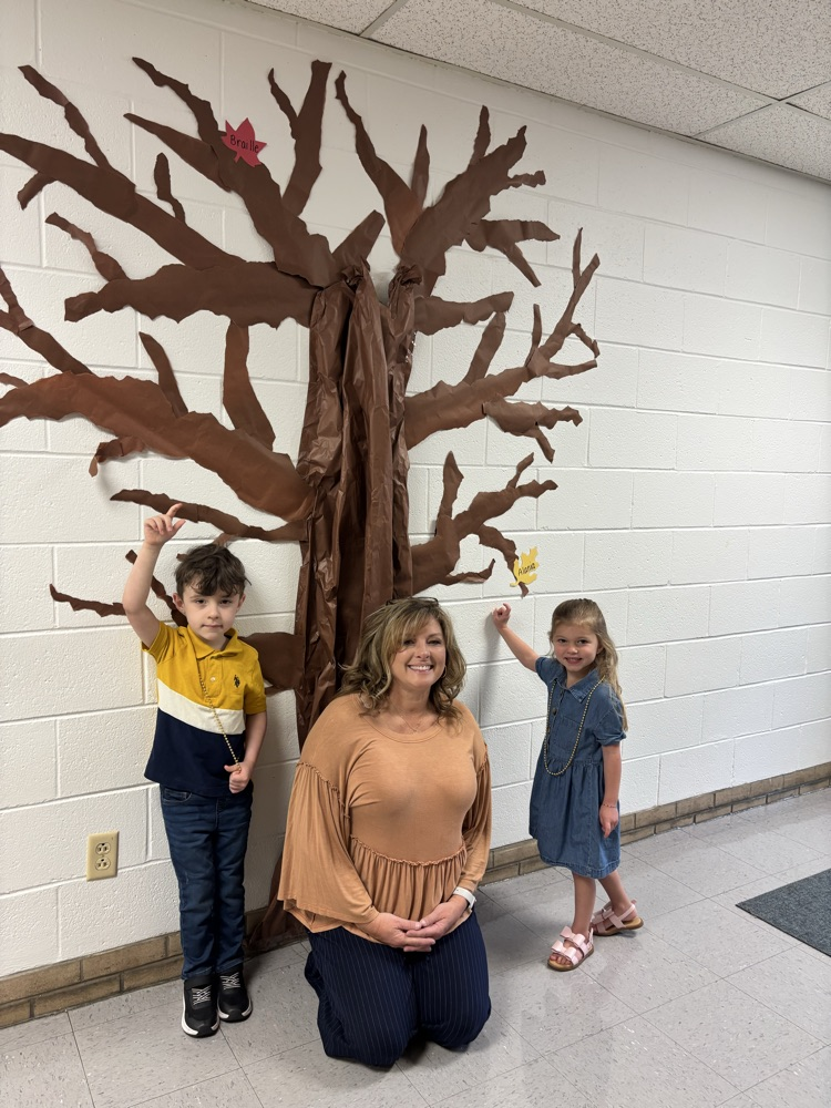 Mrs Walton and both students pictured below the tree pointing to their 🍁 