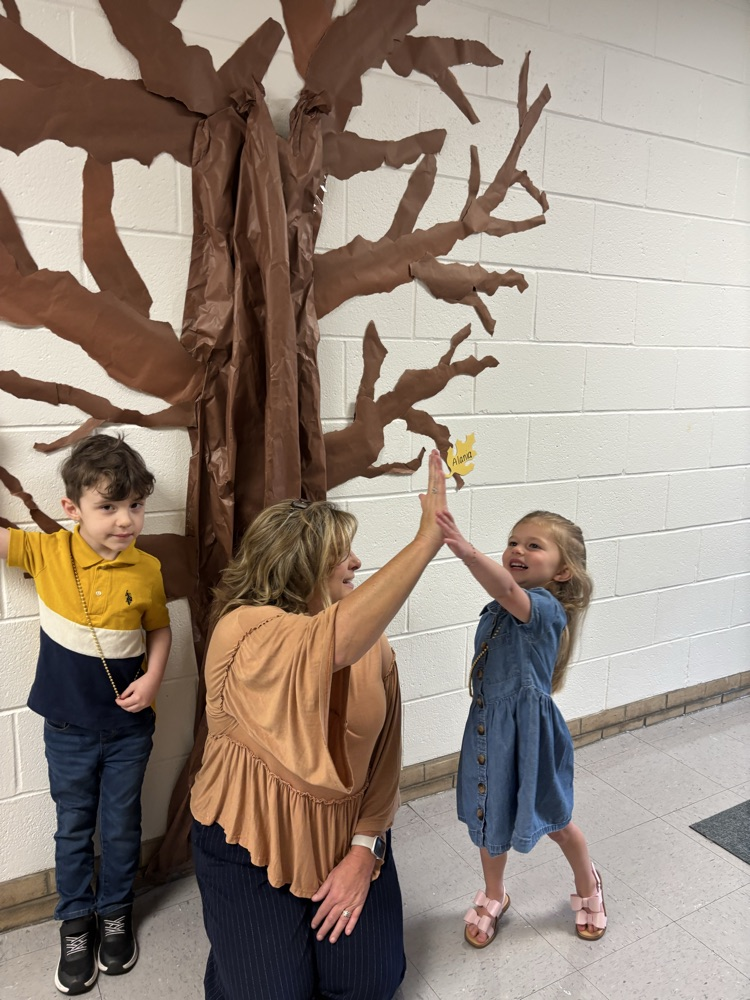 girl giving principal high five under the tree