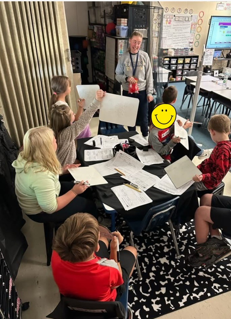 group of students around the table with whiteboards  te