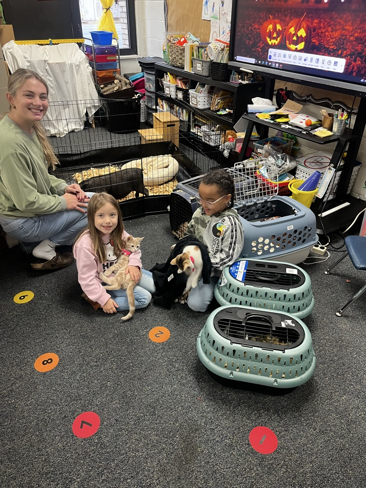 two elementary students holding animals 