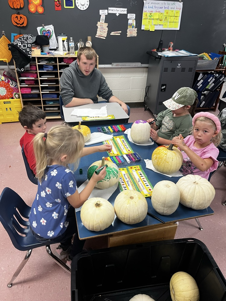 4 students painting pumpkins 