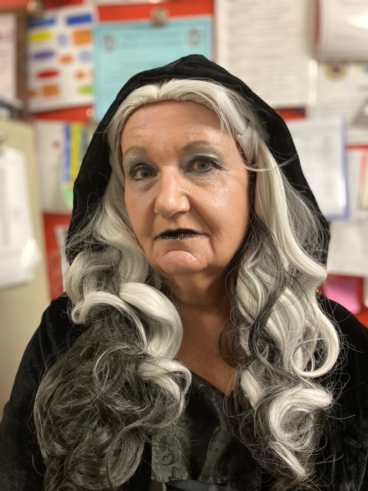 Miss Kelle the librarian in a witches costume with long gray hair. 